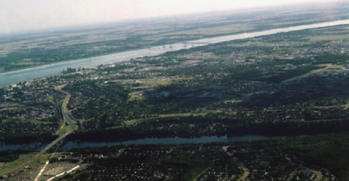 Figure 26: Trois-Rivières, Quebec - This photograph shows a flat landscape with the St. Lawrence River flowing from the right to the left of the photograph. At the bottom, flows another river. Between the two rivers there is a build-up area with buildings, roads, and bridges. There are also a lot of vegetation areas.