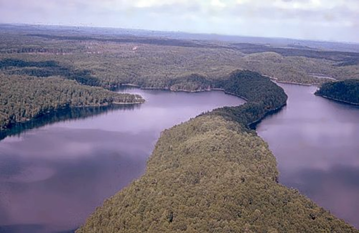 Figure 8: Témiscamingue area, Quebec - This photograph shows a flat landscape with low hills covered by trees. In the foreground, there is a lake divided into two sections by a crest crossing it.