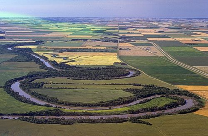 Figure 23: Red River, Manitoba - This photograph depicts a series of meanders along the Red River near Letellier in southern Manitoba. The river is located on a flat and almost featureless landscape covered with agricultural lands. The agricultural land is divided by a series of square and rectangular fields arranged like a checked board.