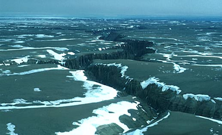 Figure 16 : Brodeur Peninsula sur lâ€™ÃŽle de Baffin, Nunavut - Cette photo montre un large plateau plat coupÃ© de gorges profondes. Il y a plusieurs bancs de neige sur le plateau.